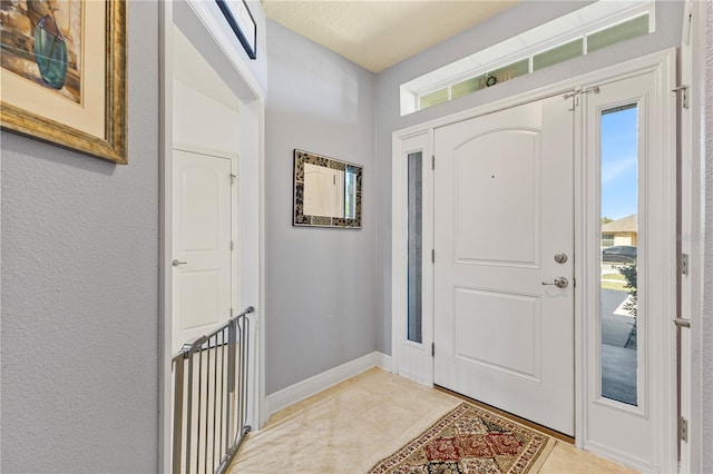 entryway featuring baseboards, light tile patterned floors, and plenty of natural light