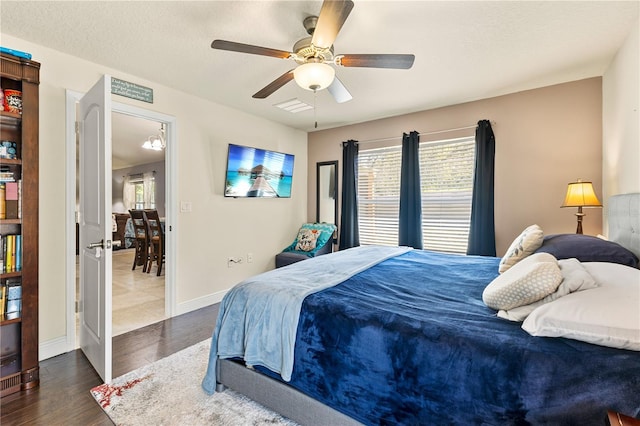 bedroom with a ceiling fan, a textured ceiling, baseboards, and wood finished floors