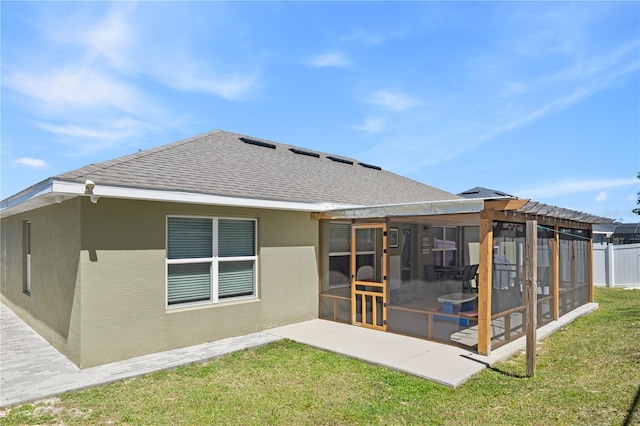 rear view of house with stucco siding, fence, a shingled roof, a sunroom, and a yard