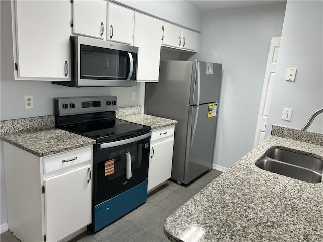 2020 Royal Bay Blvd Unit 92, Kissimmee, FL 34746 - kitchen with appliances with stainless steel finishes, a sink, white cabinets, dark tile patterned floors, and baseboards