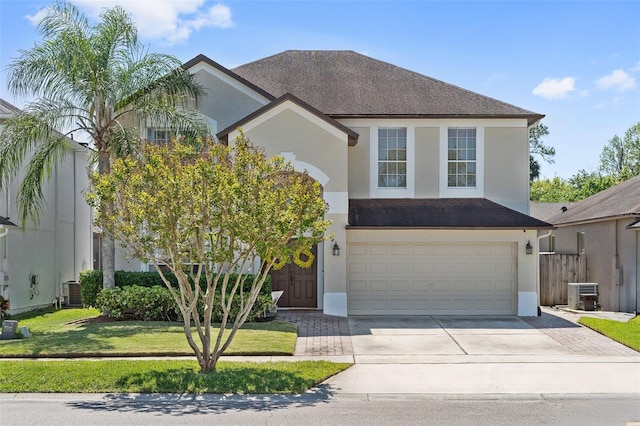traditional-style home featuring stucco siding, driveway, a front yard, central AC, and a garage