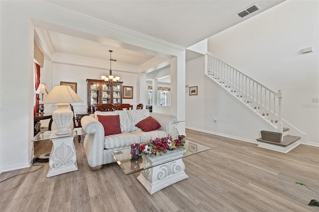 living room featuring visible vents, a chandelier, wood finished floors, and stairs