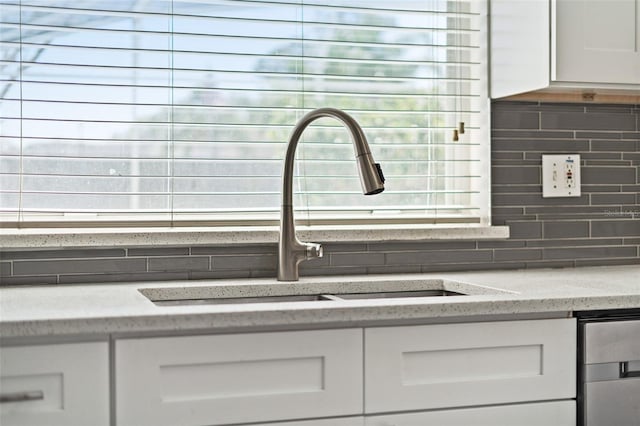 details with a sink, tasteful backsplash, white cabinets, and light stone countertops