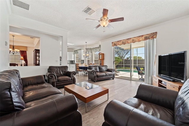 living room featuring a textured ceiling, wood finished floors, ceiling fan with notable chandelier, and visible vents