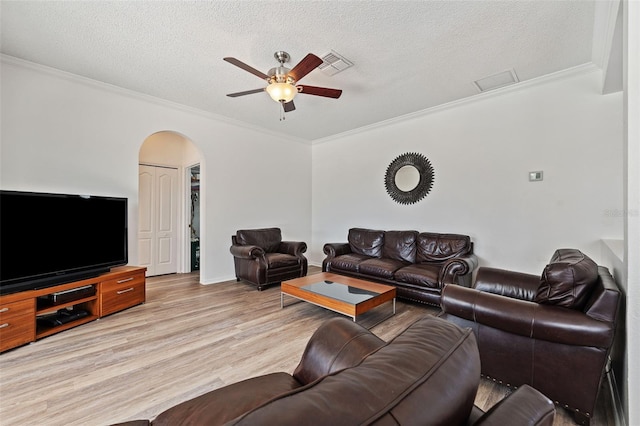 living room featuring crown molding, a ceiling fan, visible vents, and arched walkways