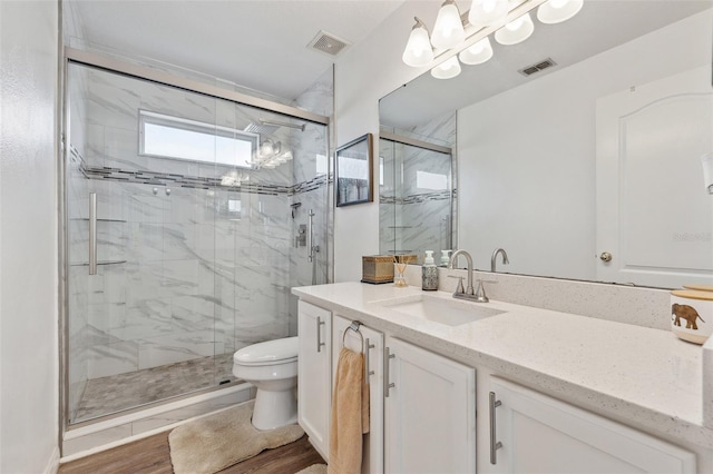 full bath featuring toilet, wood finished floors, a marble finish shower, and visible vents