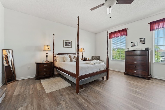 bedroom with baseboards, multiple windows, and wood finished floors