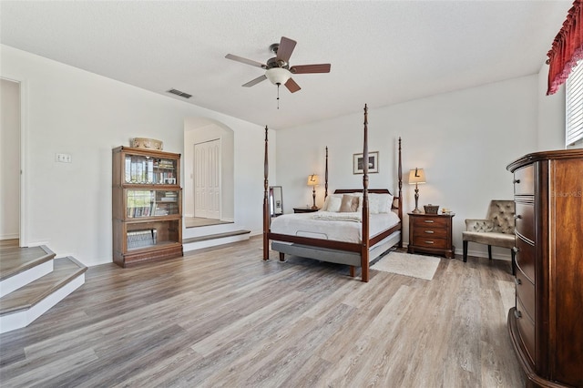 bedroom with visible vents, ceiling fan, arched walkways, and light wood-style floors