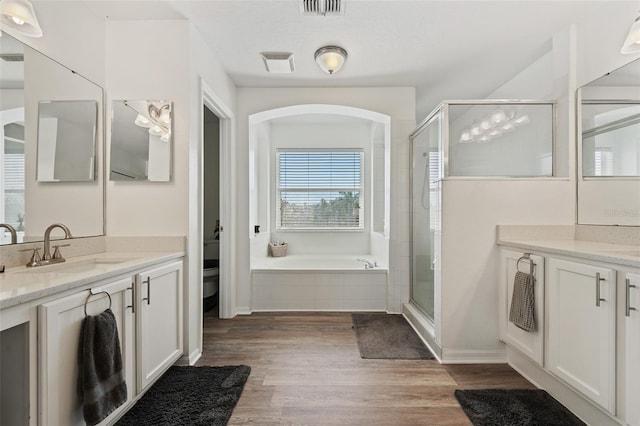 full bath featuring a shower stall, vanity, visible vents, and wood finished floors