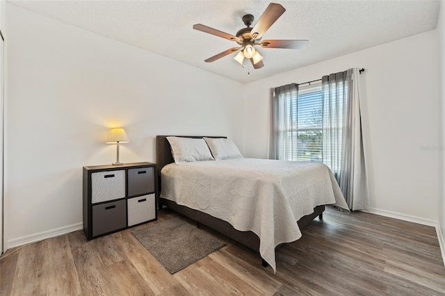 bedroom featuring a textured ceiling, baseboards, a ceiling fan, and wood finished floors