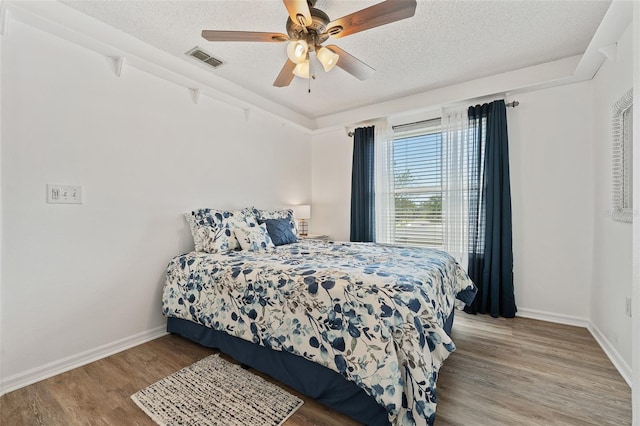 bedroom featuring visible vents, baseboards, ceiling fan, a textured ceiling, and light wood-style flooring