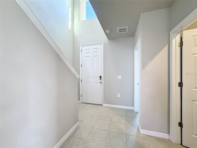 hall featuring light tile patterned floors, baseboards, and visible vents