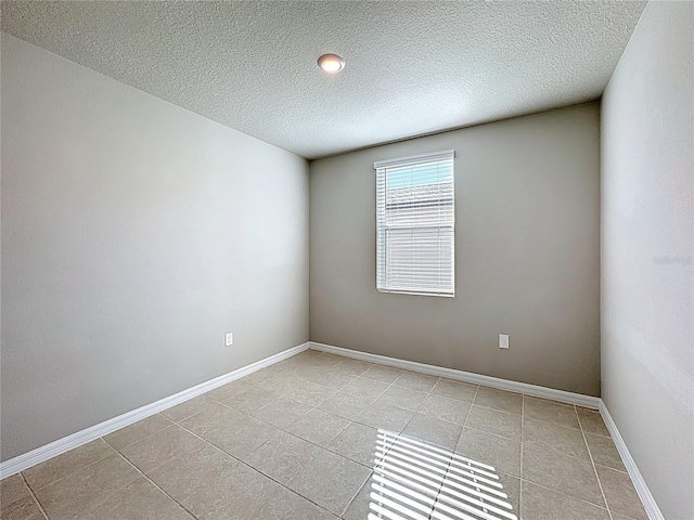 unfurnished room featuring light tile patterned flooring, a textured ceiling, and baseboards