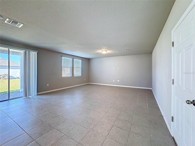 empty room featuring light tile patterned floors, visible vents, baseboards, and a textured ceiling
