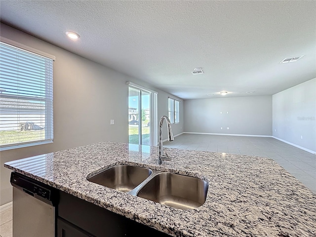 kitchen with a sink, visible vents, light stone countertops, and dishwasher