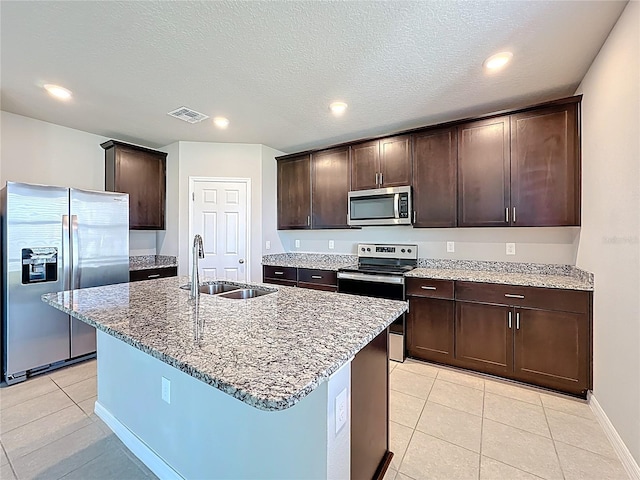 kitchen with visible vents, a sink, appliances with stainless steel finishes, light stone countertops, and dark brown cabinets