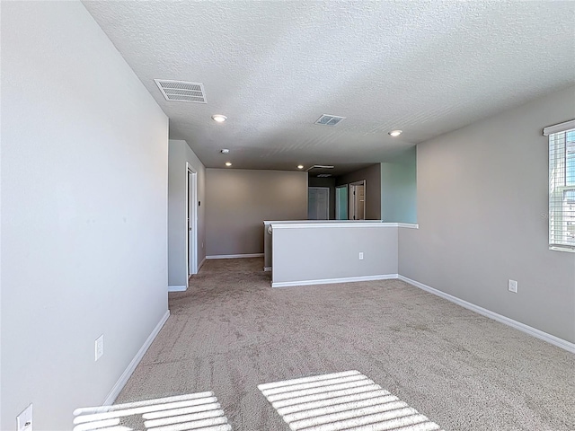 carpeted spare room featuring recessed lighting, baseboards, visible vents, and a textured ceiling