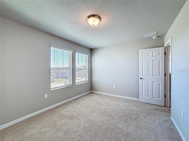 carpeted empty room with visible vents, baseboards, and a textured ceiling
