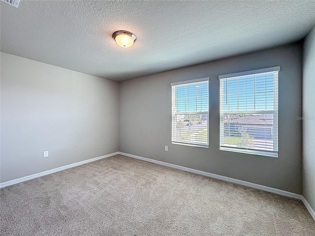 carpeted empty room featuring visible vents, baseboards, and a textured ceiling