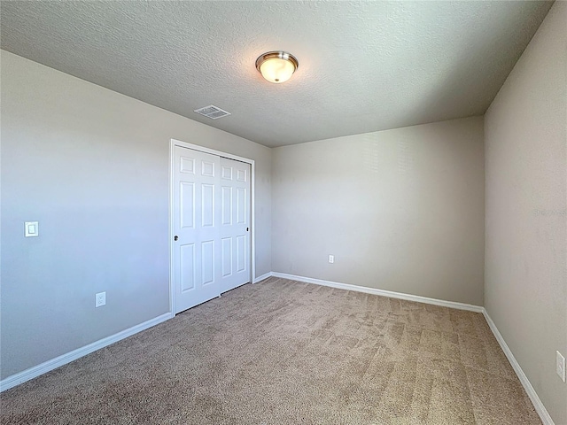 unfurnished bedroom with baseboards, visible vents, carpet floors, a closet, and a textured ceiling