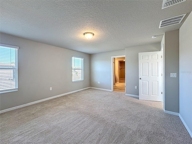 unfurnished bedroom featuring visible vents, a textured ceiling, baseboards, and carpet floors