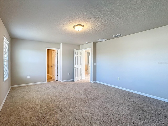 unfurnished bedroom featuring visible vents, baseboards, light colored carpet, and a textured ceiling