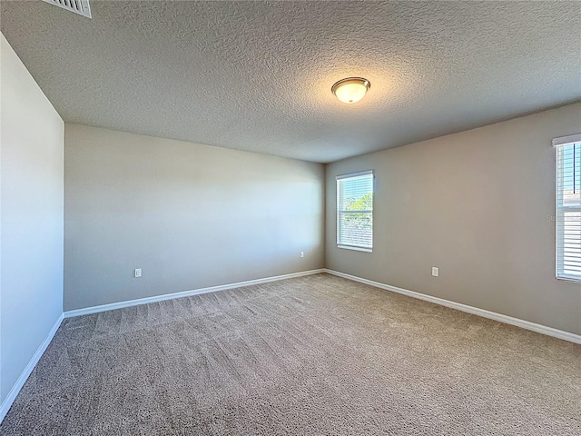 carpeted spare room with baseboards and a textured ceiling