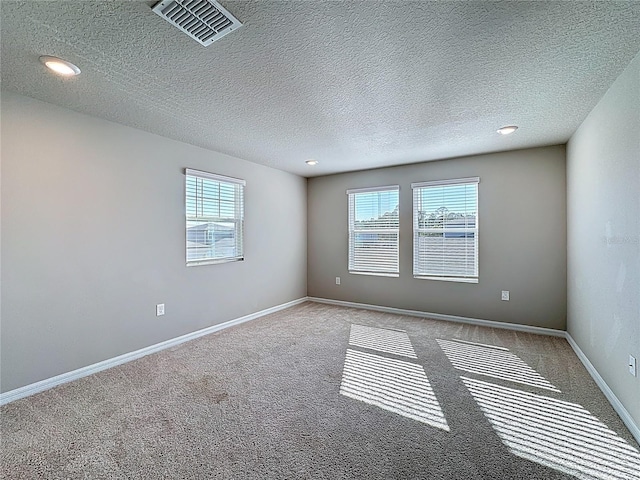 carpeted empty room featuring visible vents, baseboards, and a textured ceiling