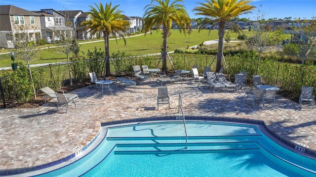 community pool with a patio area and fence