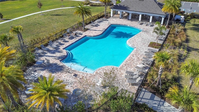 community pool with a patio area, fence, and a lawn
