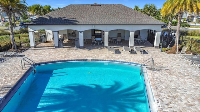 community pool with a patio, outdoor dining space, and fence