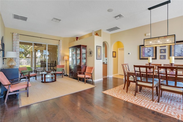 dining area with arched walkways, visible vents, and dark wood-style flooring