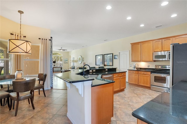 kitchen featuring a sink, dark countertops, appliances with stainless steel finishes, and a healthy amount of sunlight