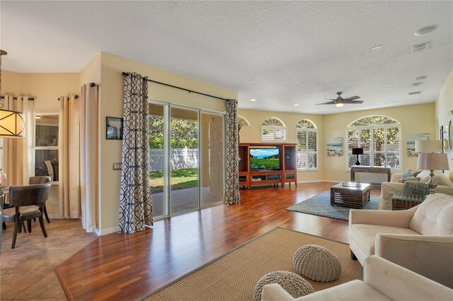 living area featuring plenty of natural light, a textured ceiling, wood finished floors, and a ceiling fan