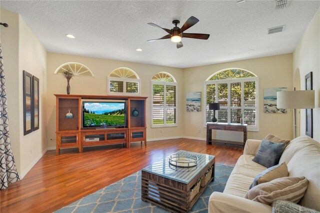 living area featuring wood finished floors, visible vents, and ceiling fan