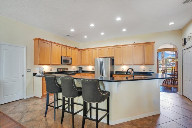kitchen with dark countertops, a breakfast bar area, visible vents, and stainless steel appliances