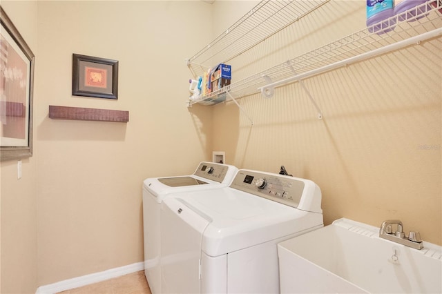 laundry room with a sink, washer and dryer, tile patterned flooring, baseboards, and laundry area
