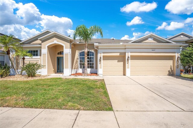 ranch-style house with stucco siding, an attached garage, driveway, and a front yard
