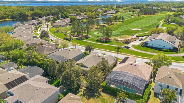 drone / aerial view featuring view of golf course, a residential view, and a water view