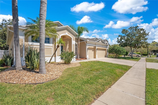 view of front of house with stucco siding, a front lawn, driveway, fence, and an attached garage