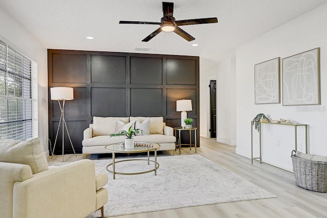 4907 21st Ave W, Bradenton, FL 34209 - living room featuring light wood finished floors, a decorative wall, a textured ceiling, and a ceiling fan
