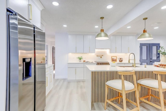 4907 21st Ave W, Bradenton, FL 34209 - kitchen featuring pendant lighting, light countertops, light wood-style flooring, stainless steel fridge, and a sink