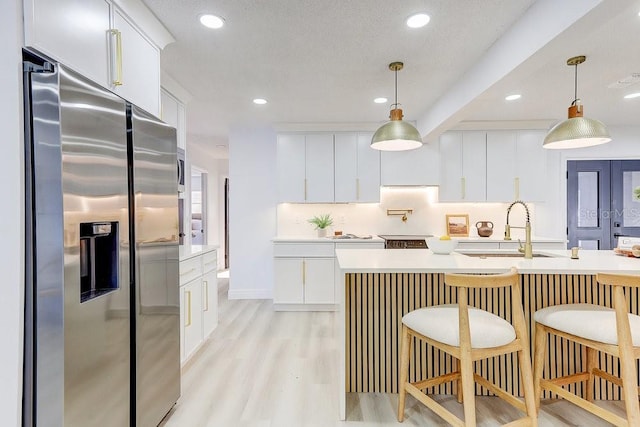 4907 21st Ave W, Bradenton, FL 34209 - kitchen featuring light wood-type flooring, pendant lighting, a sink, stainless steel fridge with ice dispenser, and light countertops