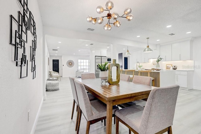 4907 21st Ave W, Bradenton, FL 34209 - dining room featuring a chandelier, visible vents, a textured ceiling, and light wood-type flooring