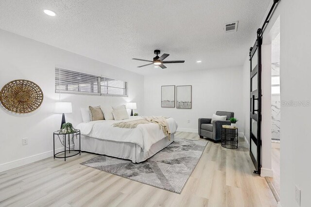 4907 21st Ave W, Bradenton, FL 34209 - bedroom featuring visible vents, a textured ceiling, light wood-style floors, and a barn door