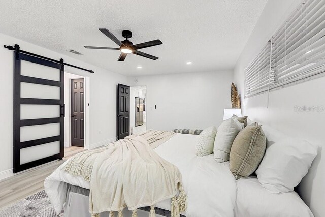 4907 21st Ave W, Bradenton, FL 34209 - bedroom with light wood finished floors, visible vents, a textured ceiling, and a barn door