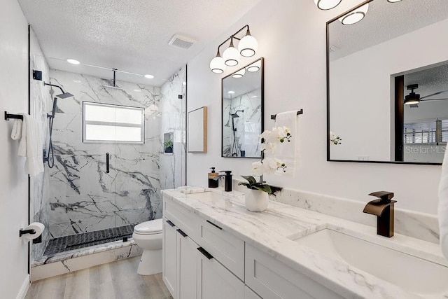 4907 21st Ave W, Bradenton, FL 34209 - bathroom featuring a marble finish shower, toilet, wood finished floors, a textured ceiling, and a sink