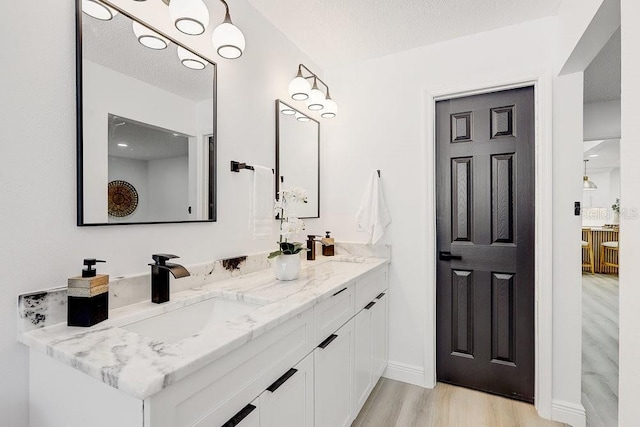 4907 21st Ave W, Bradenton, FL 34209 - bathroom featuring double vanity, a textured ceiling, wood finished floors, and a sink
