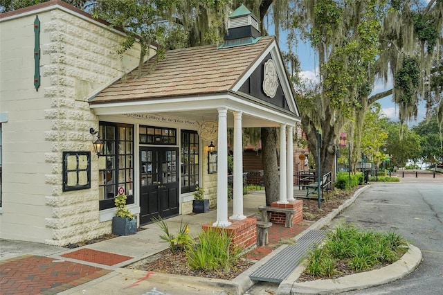 view of exterior entry with french doors and a chimney