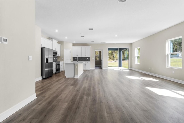 1973 E Celina St, Inverness, FL 34453 - unfurnished living room featuring healthy amount of natural light, baseboards, dark wood-style floors, and recessed lighting